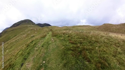 First person POV footage walking along footpath trail along a remote mountain hill trail with stunning views in rural countryside landscape