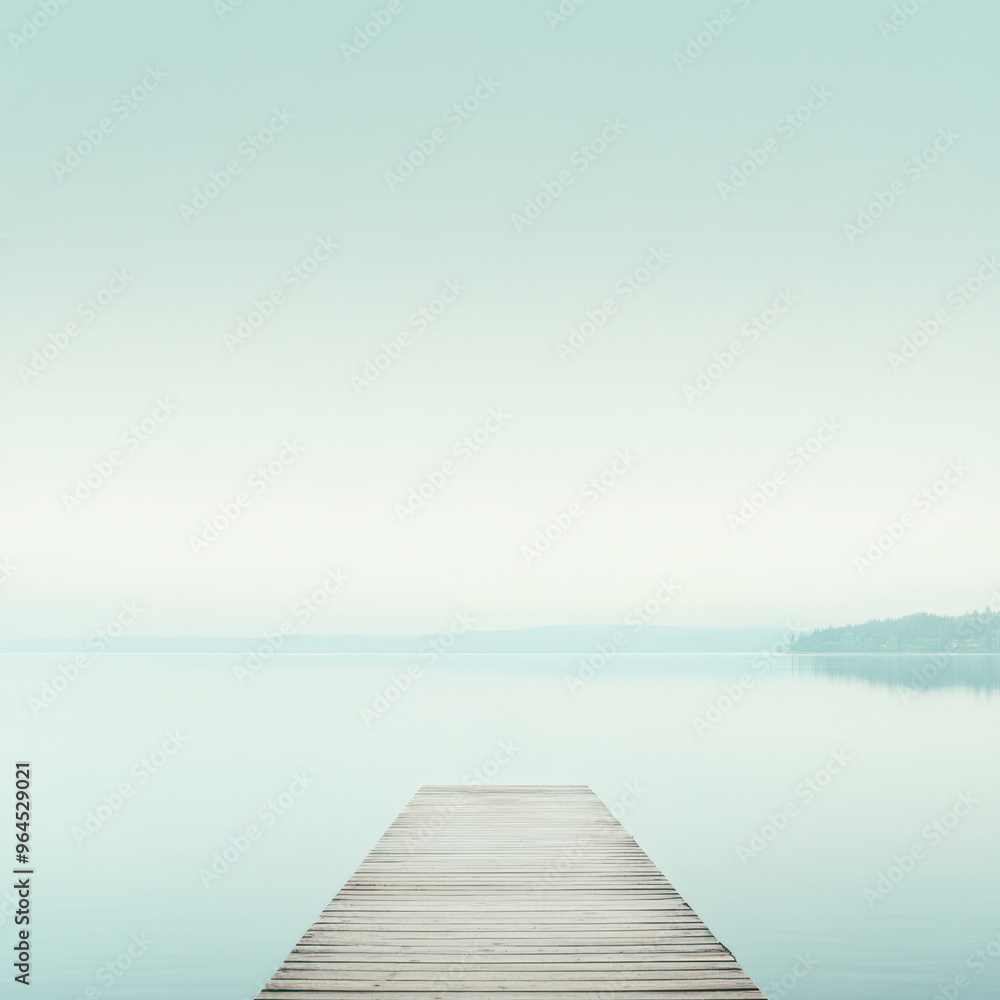 A minimalist wooden pier stretches into a calm, mist-covered lake under a pale blue sky, evoking peace and solitude.
A minimalist wooden pier stretches into a calm, mist-covered lake under a pale blue sky, evoking peace and solitude.