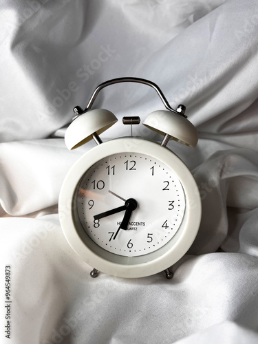 White vintage alarm clock on white textile background