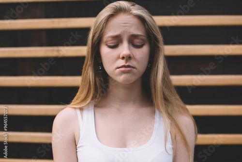 Concept of cheerless and joyless, disappointed hipster girl feeling sad and melancholy while standing on publicity area, regrettable offended Caucasian woman 20s with emotional pain on face photo