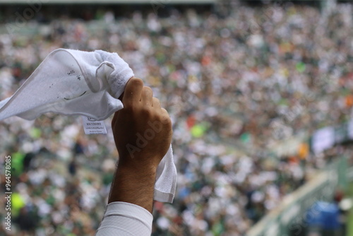 Fans celebrate passionately at a sports event, waving white towels in the air during a thrilling match in a packed stadium