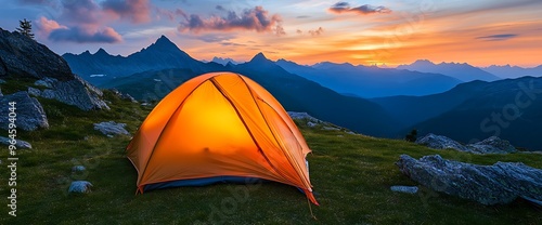 Illuminated tent on a mountaintop with a sunset in the background.