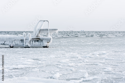 Diving board covered with ice and icicles in winter. Frozen sea on a very cold day.