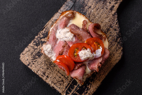 Sandwich with brioche bun, roast beef, tomatoes, stracciatello photo