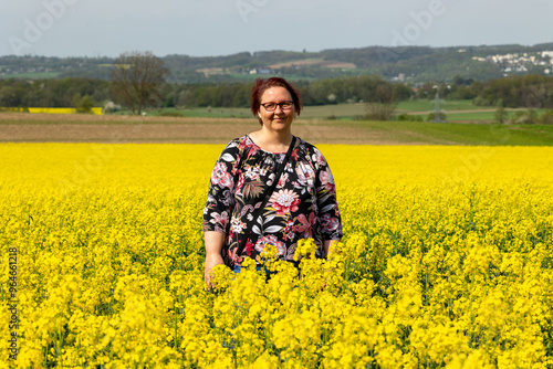 A woman is standing in a field of Blooming rapeseed