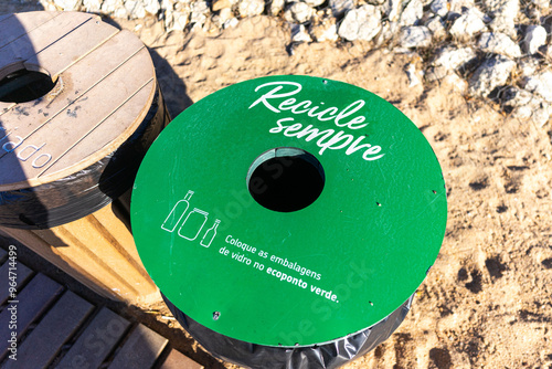 Colorful recycling bins standing on a sandy beach in Portugal, surrounded by golden sand, promoting environmental awareness and sustainability in a serene coastal setting. photo