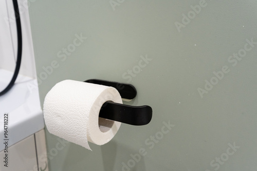 In an organized and wellarranged bathroom, a sleek black holder elegantly displays a single roll of toilet paper, ensuring that it is easily accessible for immediate use whenever needed photo