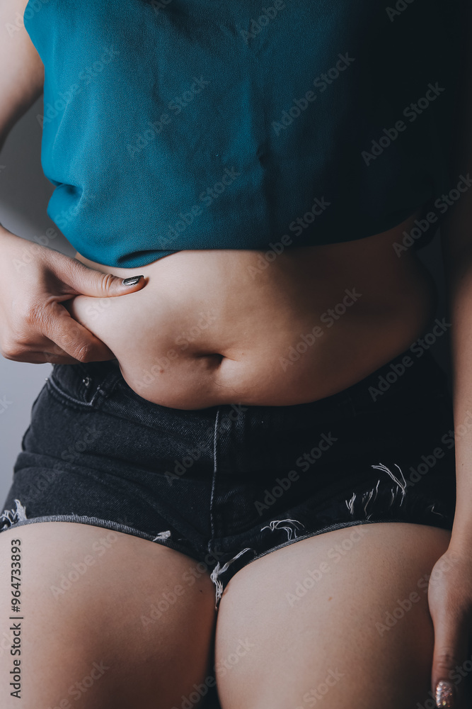Fototapeta premium fat woman, fat belly, chubby, obese woman hand holding excessive belly fat with measure tape, woman diet lifestyle concept