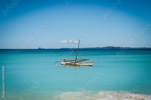 A tranquil day at Paradise Beach in Nosy Be with a rustic fishing boat floating on calm turquoise waters