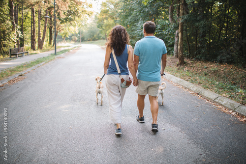 Canvas Print Rear view of couple walking dogs in the park