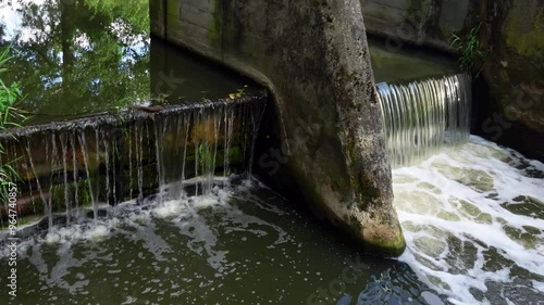 A water weir that dams up water on a small river. Engineering hydrotechnical structures that locally raise the water level. Static intake taken in natural lighting photo