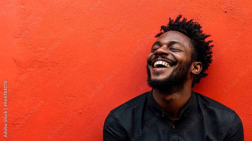 A man is smiling and laughing with joy, standing in front of a bright red backdrop. A man is smiling and laughing with joy, standing in front of a bright red backdrop.