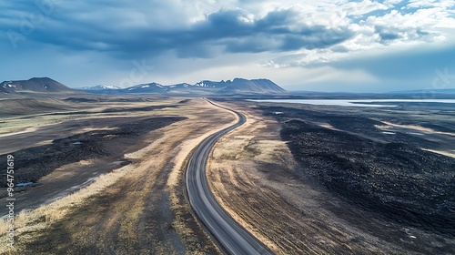 Aerial view of a winding road through a barren landscape with mountains in the distance.