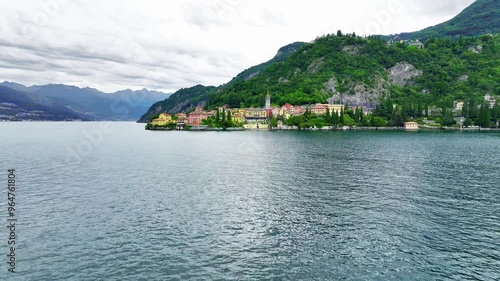 Dolly-in shot with a drone flying over lake Como and focusing on the city Varenna in Italy during summer season sowing bright colours