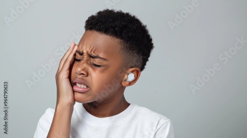 Black short hair boy holding his head in pain and frowning, close-up with pained expression due to earache