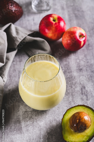 Organic mixed drink of avocado, apple and yogurt in glass on table vertical view