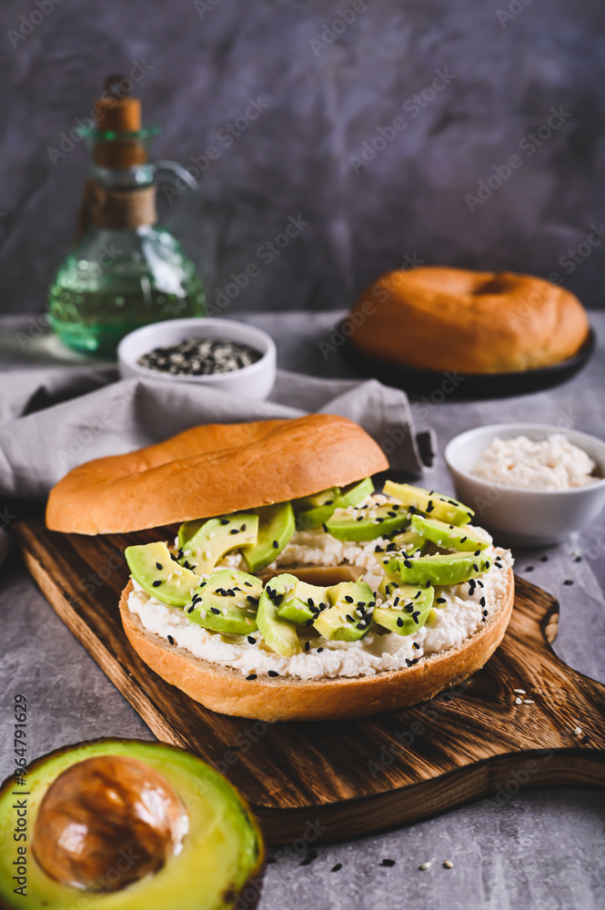 Delicious ricotta and avocado bagel on a breakfast board vertical view Delicious ricotta and avocado bagel on a breakfast board vertical view