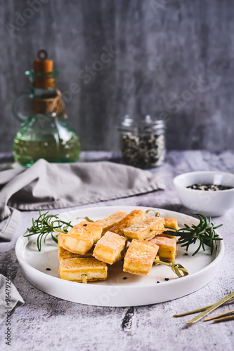 Obraz na płótnie Spicy fried tofu on skewers and rosemary on a plate on the table vertical view w salonie