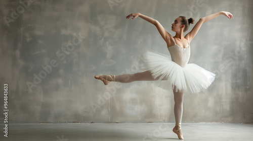 Ballerina striking a poised arabesque in a white tutu against a muted gray background. Her elegance and control emphasize the discipline of ballet