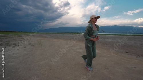 Young sports woman running on lake shore on twilight