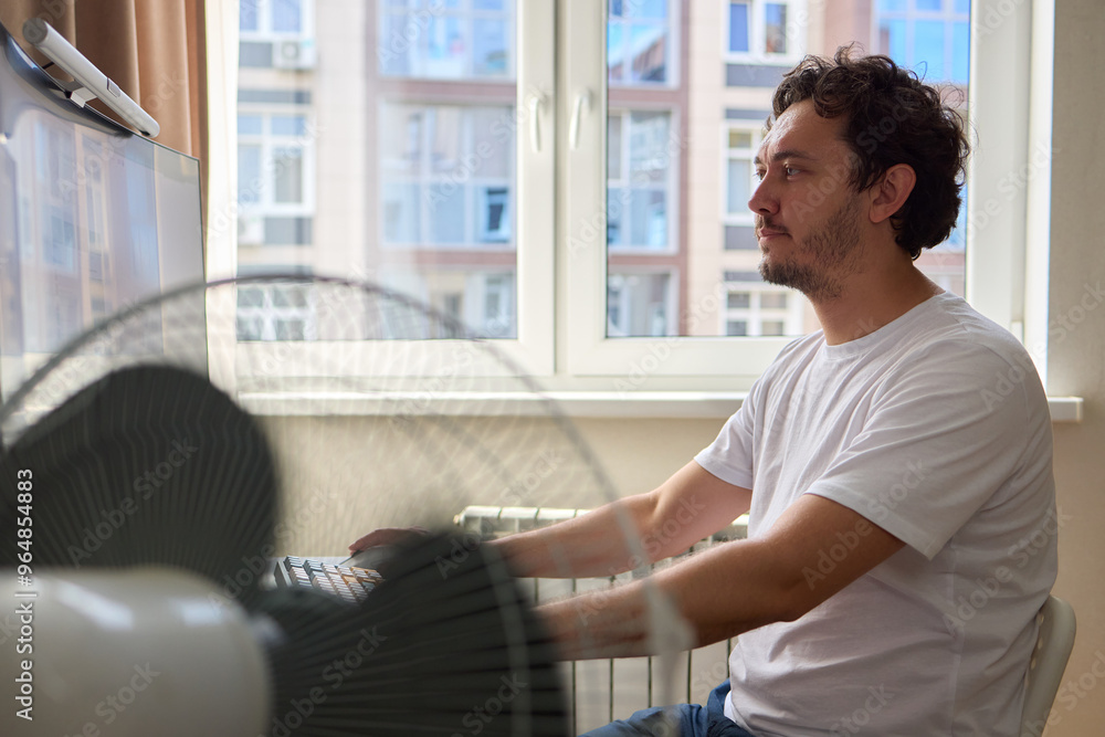 Fototapeta premium A Focused Professional Engaged in Work from Home in a Cozy Environment While Using a Fan