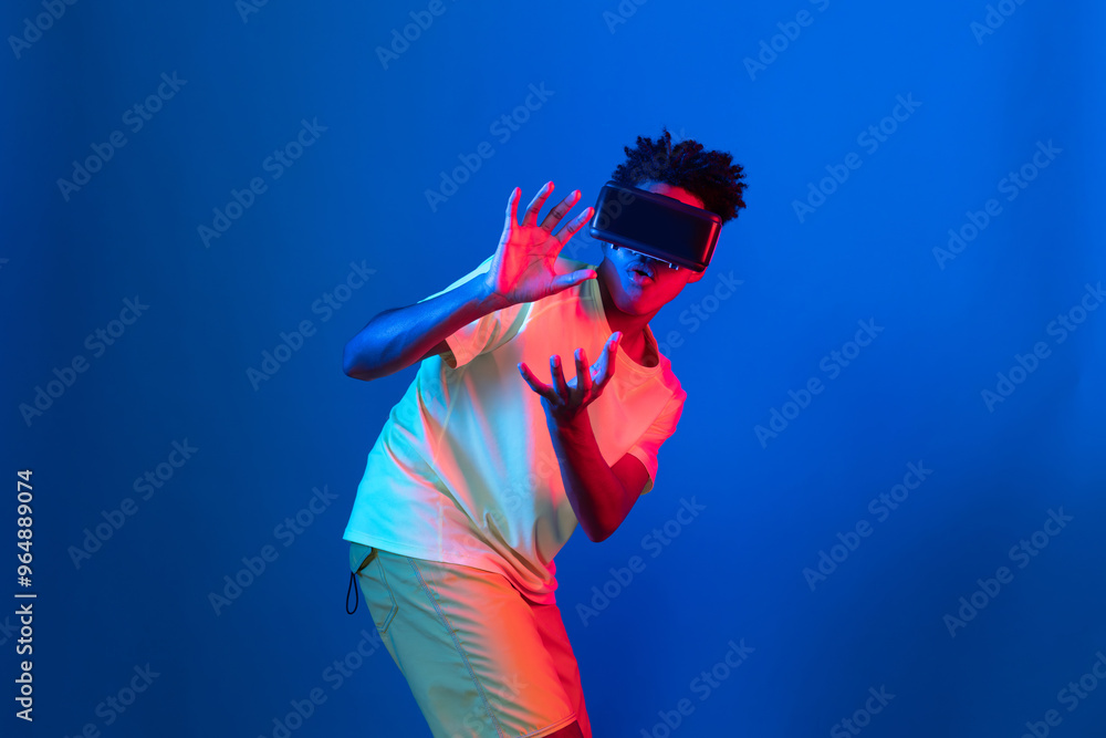 Young African American basketball gaming player wearing VR bouncing pose on blue pink neon light connecting digital futuristic technology virtual reality at metaverse world playing court. Contrivance. Young African American basketball gaming player wearing VR bouncing pose on blue pink neon light connecting digital futuristic technology virtual reality at metaverse world playing court. Contrivance.
