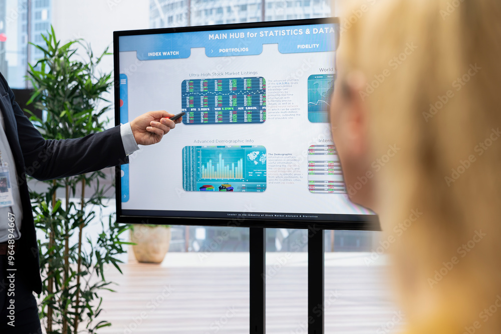 Agent presenting stock market diagrams with charts and stock figures on big screen in workplace. Broker showing forex investment listings displayed on display in financial department Agent presenting stock market diagrams with charts and stock figures on big screen in workplace. Broker showing forex investment listings displayed on display in financial department