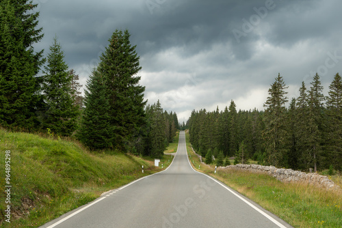 une route sans fin en montagne sous un ciel orageux