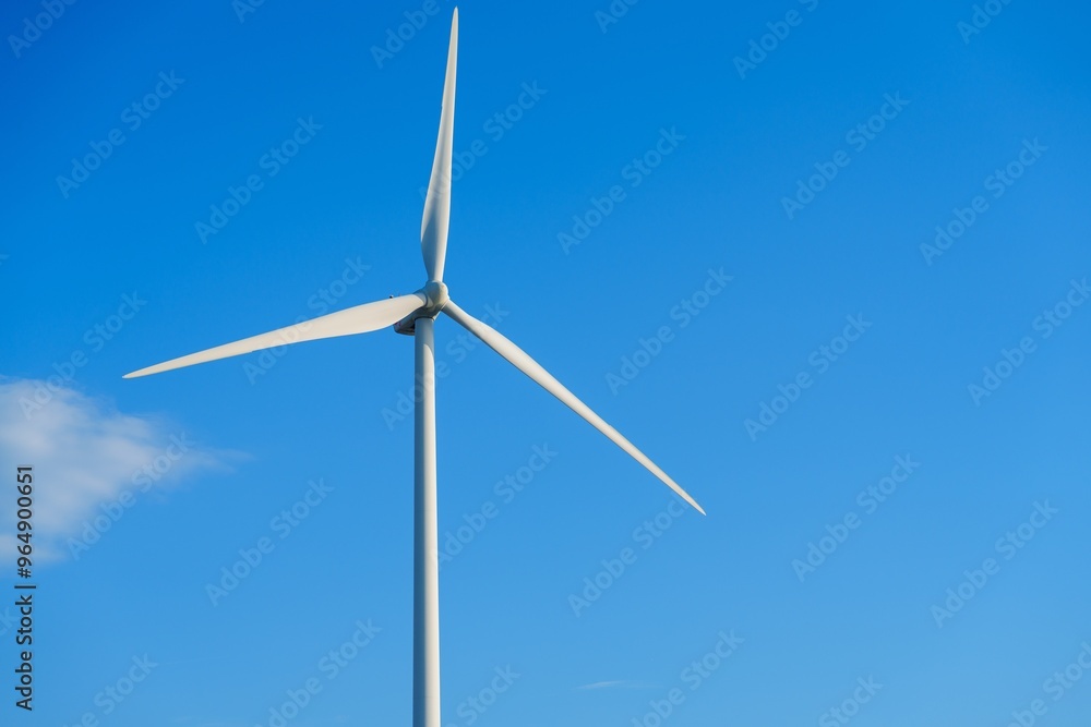 A large white wind turbine with three blades towers against a clear blue sky, symbolizing clean energy. It harnesses wind power for sustainable electricity generation, contributing to a greener future A large white wind turbine with three blades towers against a clear blue sky, symbolizing clean energy. It harnesses wind power for sustainable electricity generation, contributing to a greener future