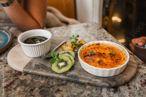 Obraz na plátně Crème Brûlée and Chocolate Mousse with Fresh Kiwi on a Marble Plate