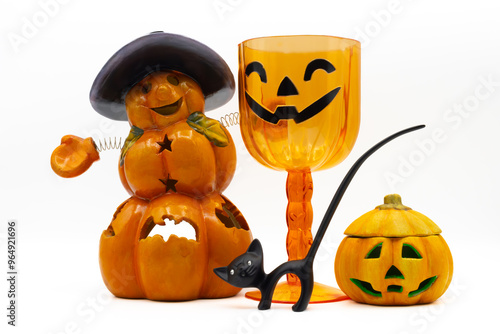 Jack O Lanterns, a black cat figurine and a plastic glass isolated on white background. Ceramic candle holders in the shape of a halloween pumpkin.
