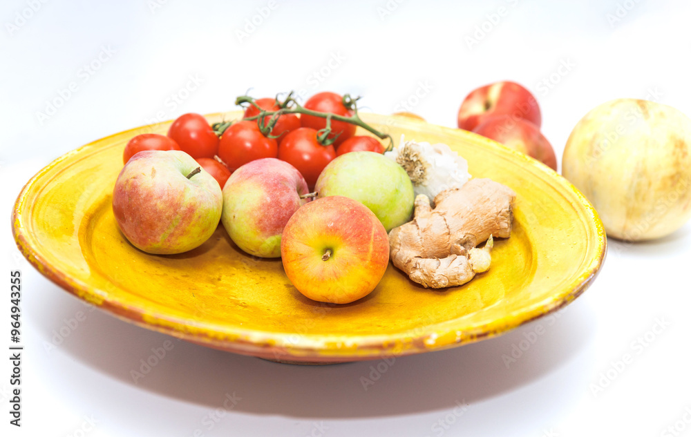 Fresh, colorful fruits and vegetables on a yellow plate, apples, tomatoes, ginger, healthy food concept Fresh, colorful fruits and vegetables on a yellow plate, apples, tomatoes, ginger, healthy food concept