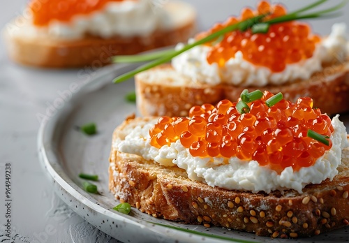 Two caviar toasts baguette canape with butter and red salmon caviar top view on grey concrete background, festive luxury delicacy and appetizer.