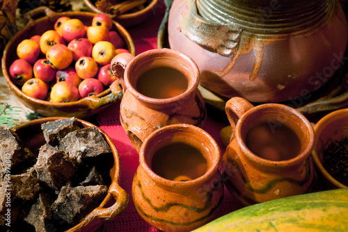 Pleasant composition of several handmade clay cups next to a clay pot and spices.