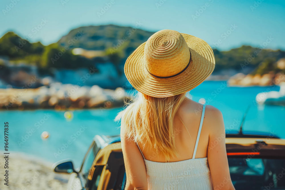 Fototapeta premium Young woman traveler in a hat standing near her car during summer holiday on the sea.