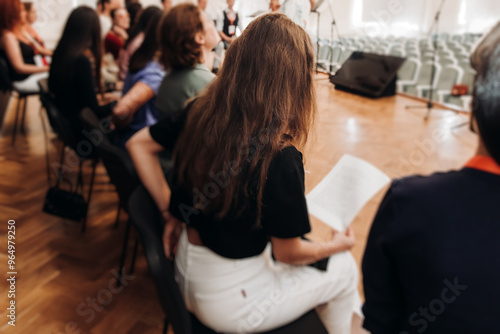 Choir rehearsal, vocal class singing in the auditorium hall, group of students on stage holding white sheets and singing, orchestra vocals class in music school with a teacher, adults sing in chorus