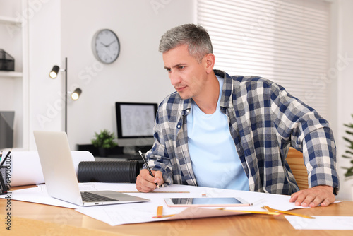 Architect making engineering drawing at wooden table in office