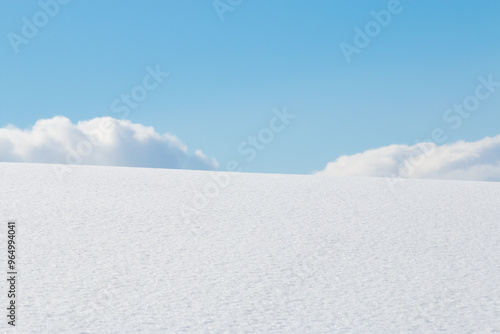 Fluffy white clouds and blue sky over snow field winter landscape background