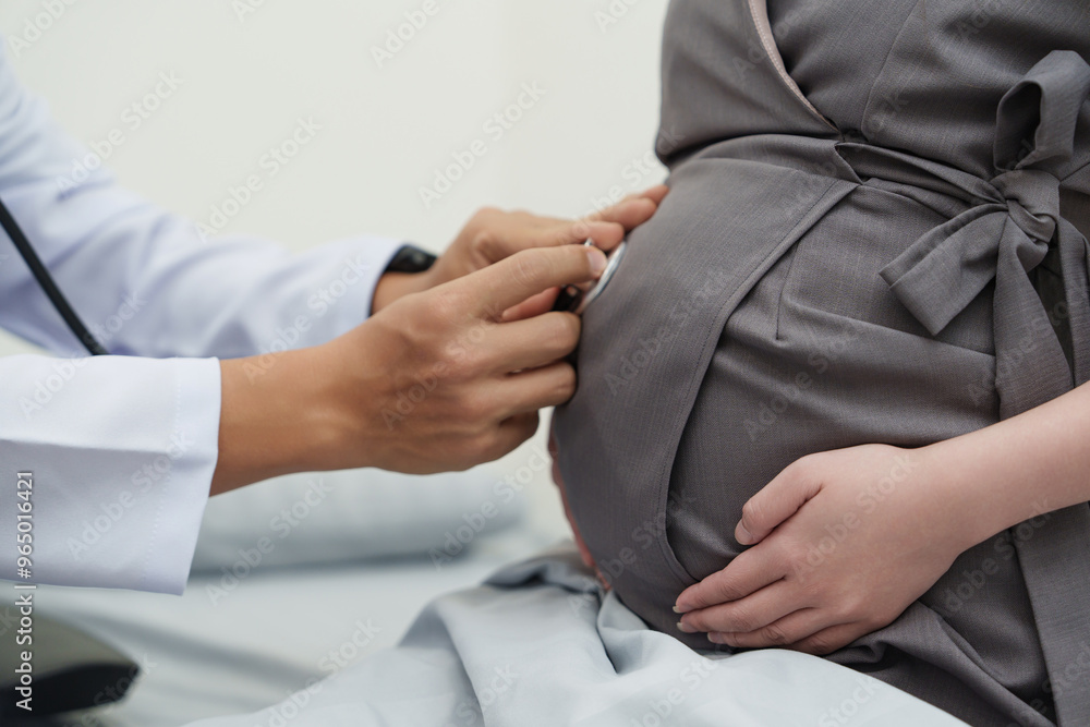 Obraz premium Close-up of doctor using stethoscope on pregnant woman's belly during prenatal checkup, monitoring baby's heartbeat for maternal and fetal health care.