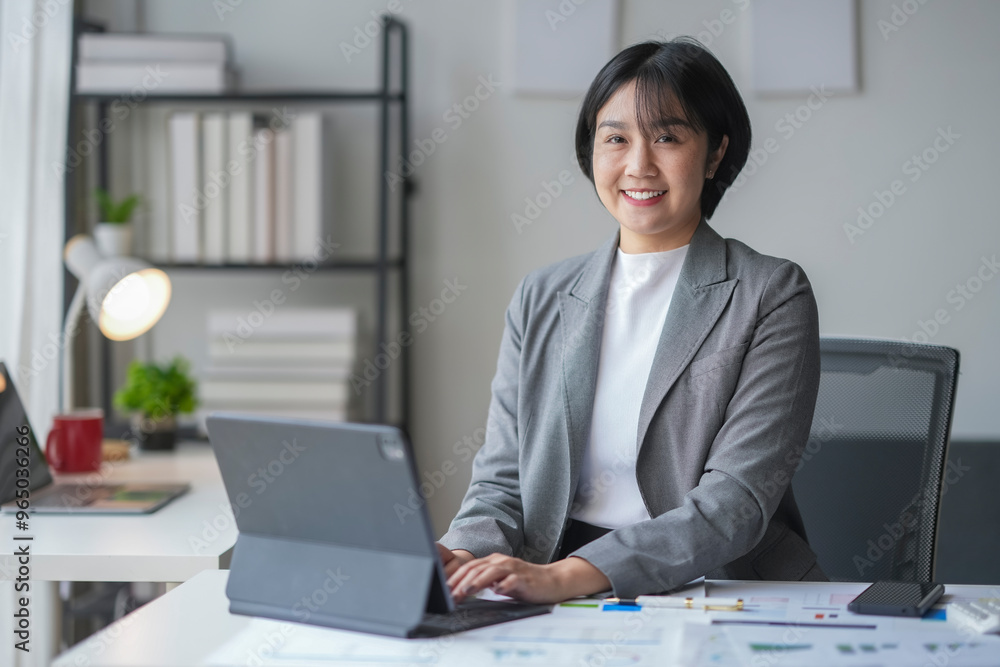 Businesswoman smiling while working on digital tablet at office desk Businesswoman smiling while working on digital tablet at office desk
