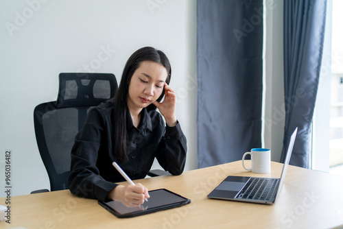 Asian businesswoman feeling tired working on tablet with laptop on desk photo