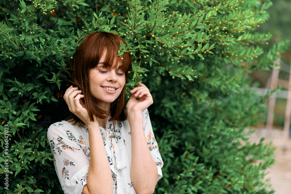 Frustrated woman with red hair leaning against bush covers ears in distress Frustrated woman with red hair leaning against bush covers ears in distress
