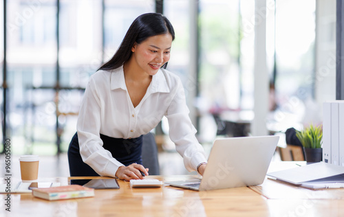 Business asian woman or female worker using a laptop computer to analyse her financial data.business people research or financial strategy in company concept. Laptop white screen mockup.