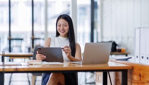 Business asian woman or female worker using a laptop computer to analyse her financial data.business people research or financial strategy in company concept. Laptop white screen mockup.