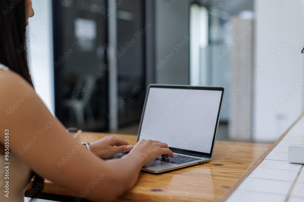Fototapeta premium Business asian woman or female worker using a laptop computer to analyse her financial data.business people research or financial strategy in company concept. Laptop white screen mockup.