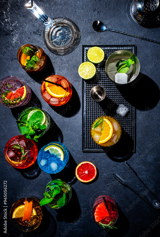 Alcoholic cocktails on bar counter, top view. Mixology and bartending concept. Set of colorful drinks for party. Black background, bar tools, hard light, top view Alcoholic cocktails on bar counter, top view. Mixology and bartending concept. Set of colorful drinks for party. Black background, bar tools, hard light, top view