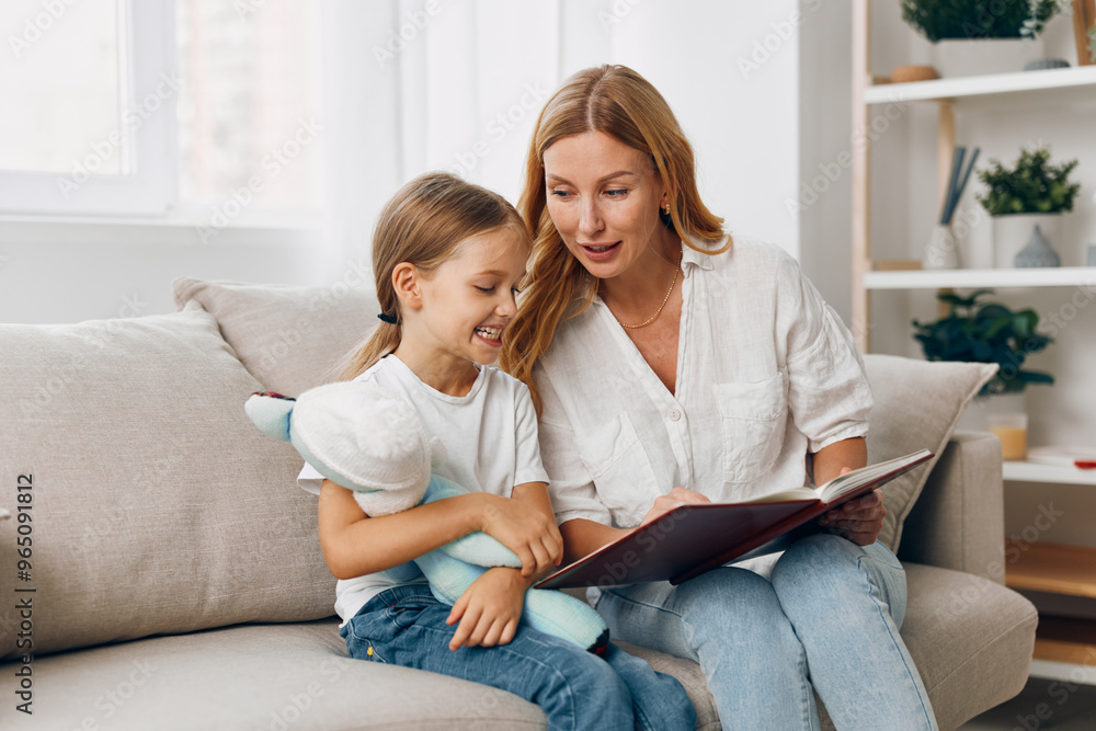 Mother and daughter bonding time on cozy couch with a storybook and teddy bear Mother and daughter bonding time on cozy couch with a storybook and teddy bear