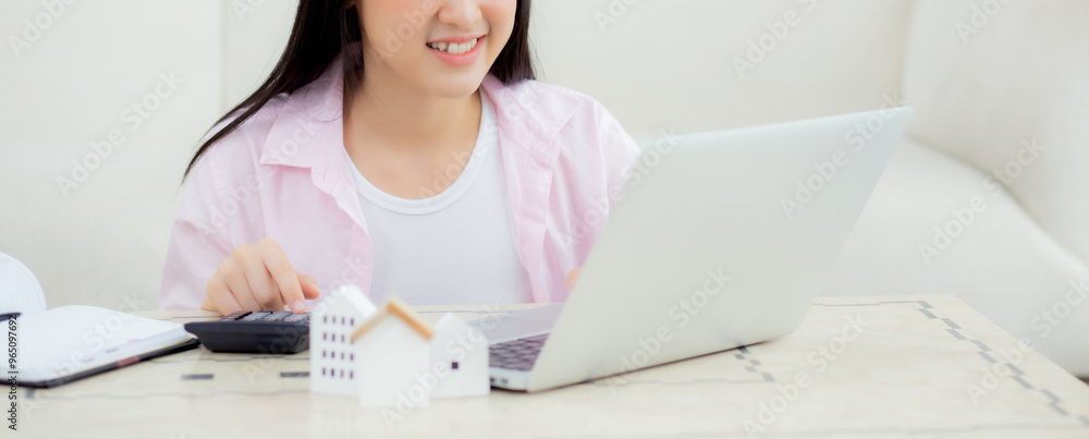 Φωτογραφία Young asian woman sitting and planning and calculate expense and mortgage with calculator and home on desk, insurance and budget of residential, loan and residence, business and property concept