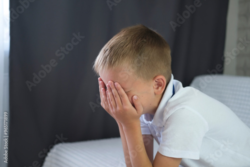 One sad little boy sitting on sofa at home. Child abuse. Anxiety and stress. Concept of bullying, depressive stress or disappointment, sadness.