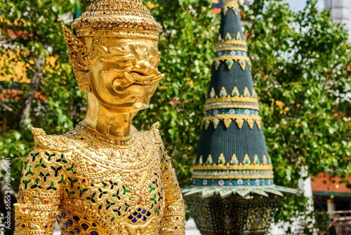 Asurapaksi, a gold giant-and-bird chimera statue beside a panom mak (banana leaf offering) sculpture at the Temple of the Emerald Buddha (Wat Phra Kaew) inside the Grand Palace - Bangkok, Thailand 
 photo